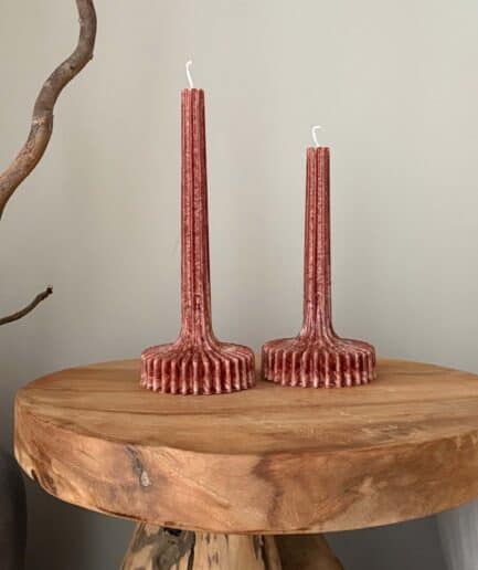 Dvi rankų darbo palmių vaško žvakės ant medinio stalo.
