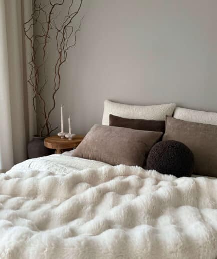 Miegamojo lova su minkštu pūkuotu antklode ir dekoratyviniais pagalvėmis.